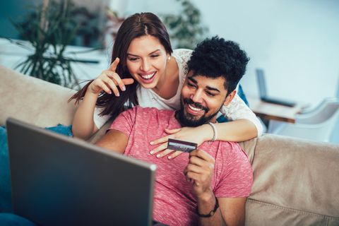 Ein junges Paar sitzt vor dem Laptop und shoppt online