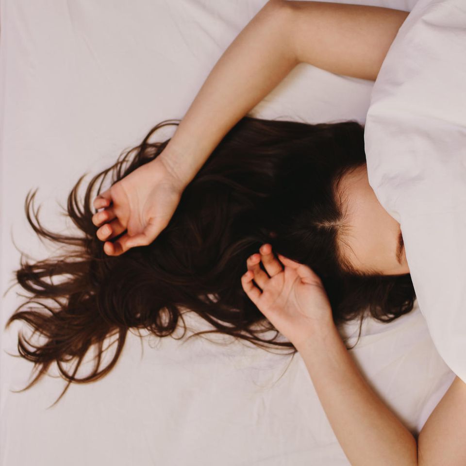 Frau unter der Bettdecke: Das passiert wirklich, wenn du mit nassen Haaren schläfst