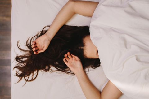 Frau unter der Bettdecke: Das passiert wirklich, wenn du mit nassen Haaren schläfst