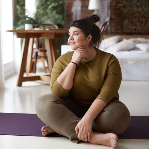 Zufrieden Frau auf der Yogamatte | Psychologie: 5 Strategien für mehr Entschlossenheit