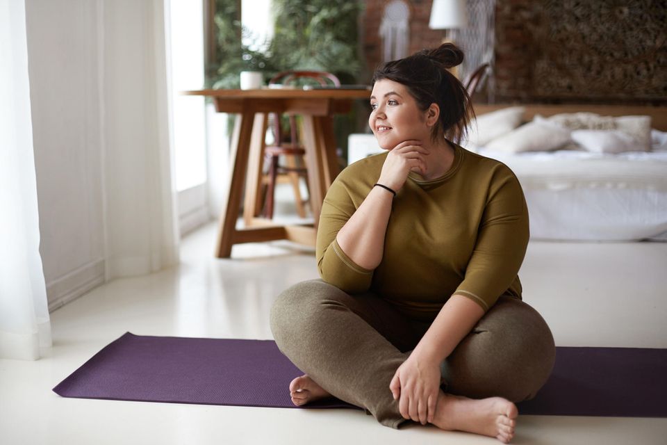 Zufrieden Frau auf der Yogamatte | Psychologie: 5 Strategien für mehr Entschlossenheit
