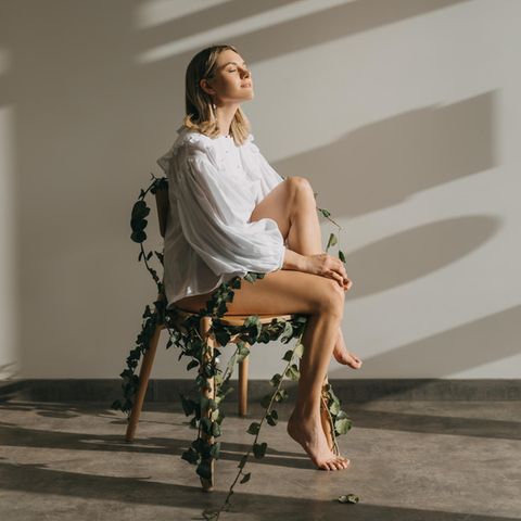 junge Frau sitzt auf einem Stuhl und trägt eine weiße Bluse