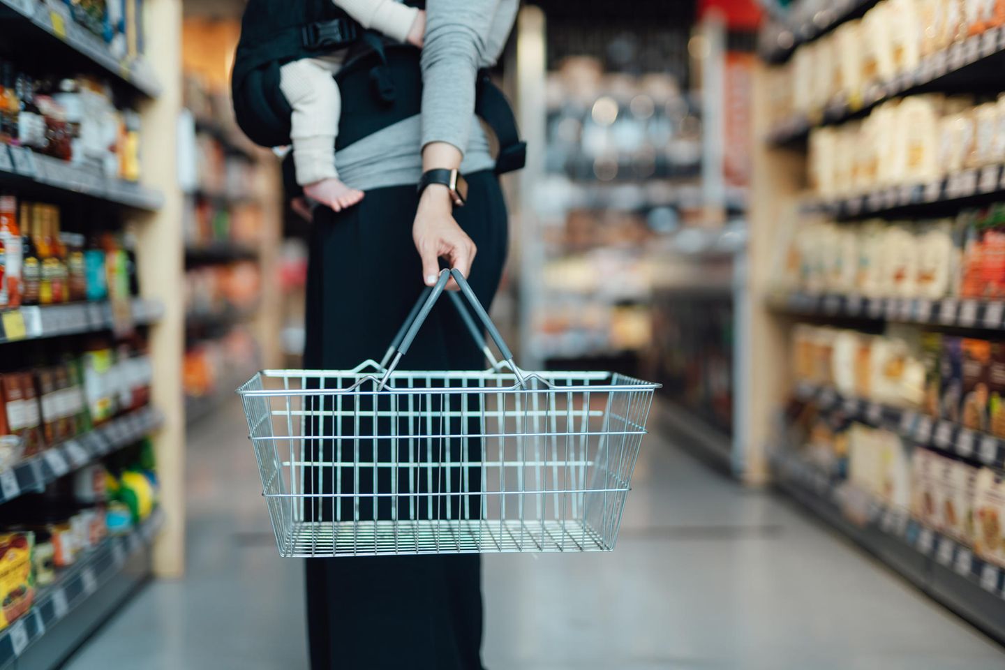 Frau mit Baby vor Supermarktregal
