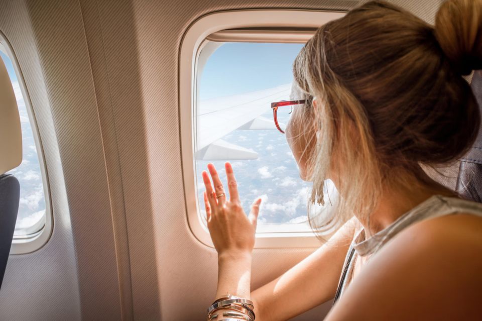 Teamtalk: eine blonde Frau schaut aus einem Flugzeugfenster