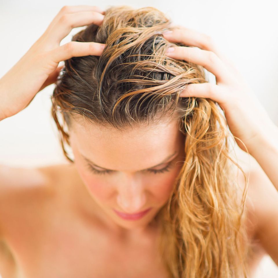 Klettenwurzel Haaröl: Frau massiert Öl ins Haar