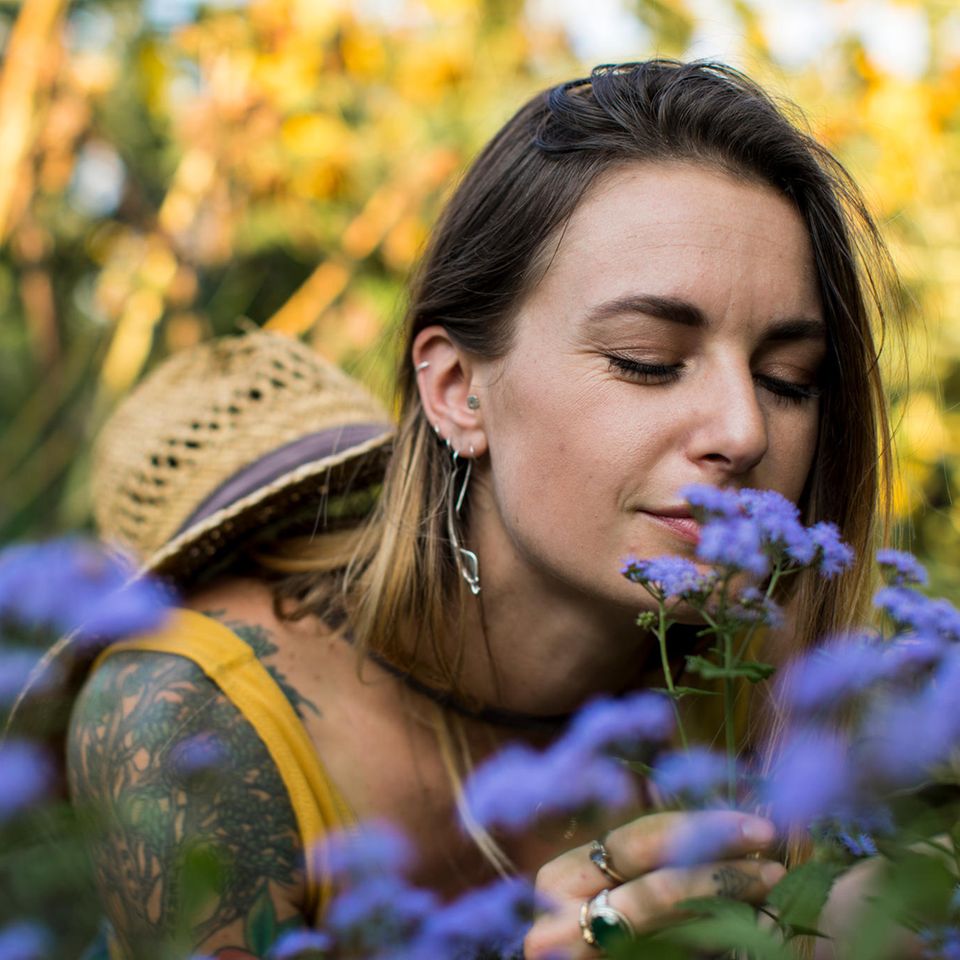 Judka Strittmacher: eine Frau riecht an violetten Blumen
