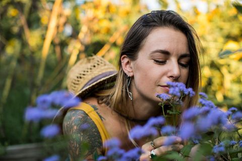 Judka Strittmacher: eine Frau riecht an violetten Blumen