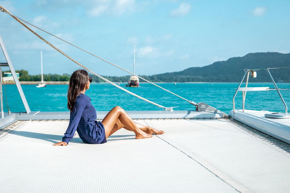 Millionärin mit 33: Eine Frau sitzt alleine auf dem Deck eines Segelboots