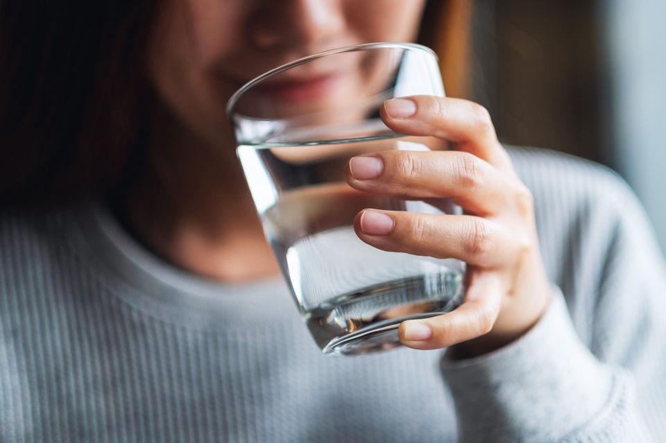 Life Hack: Frau trinkt Wasser aus einem Glas.