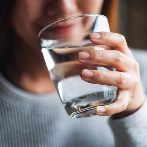 Life Hack: Frau trinkt Wasser aus einem Glas.