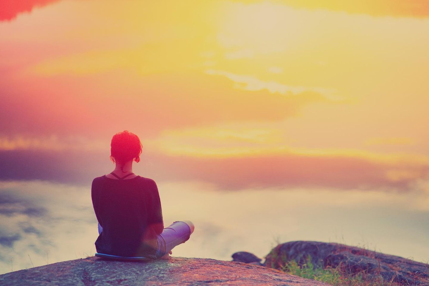 Psychologie: Eine Frau sitzt auf einem Berg und denkt nach