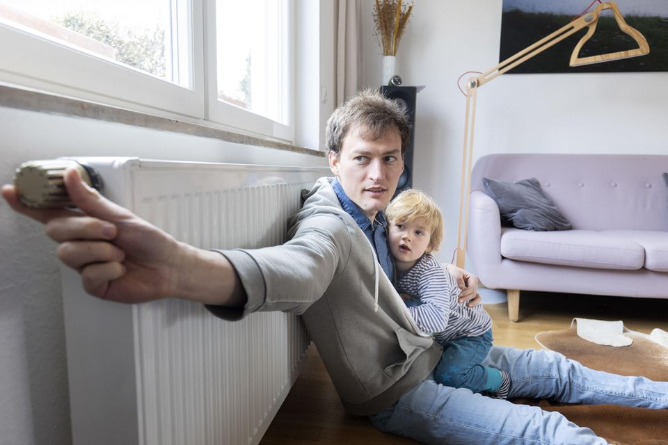 Gasumlage: Ein Vater sitzt mit seinem Kind an einer Heizung.