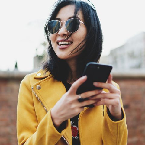 Junge fröhliche Frau mit Smartphone: 3 Gewohnheiten, die unserer mentalen Gesundheit nicht so schaden wie gedacht