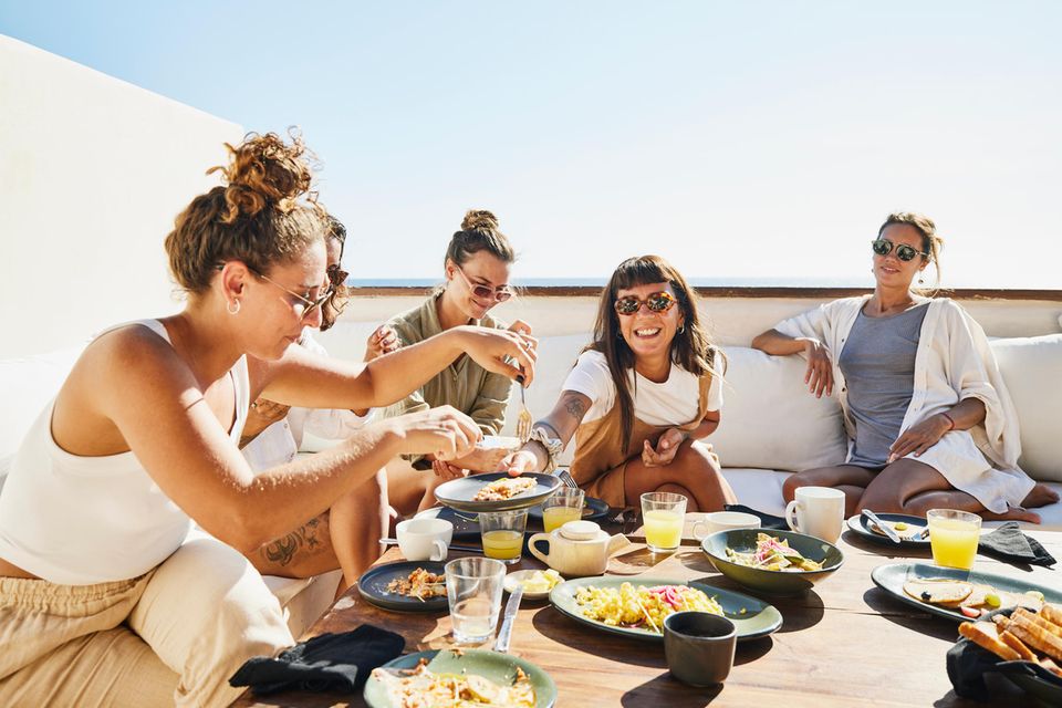 Wochenendhoroskop: Frauen sitzen zusammen am Tisch und frühstücken.