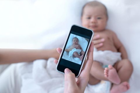 Ein Baby wird mit dem Handy fotografiert
