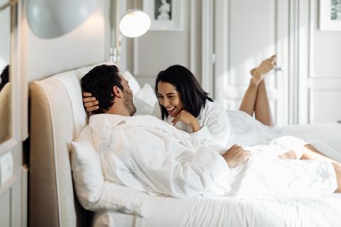 Ein Mann und eine Frau liegen im Bett und lachen.