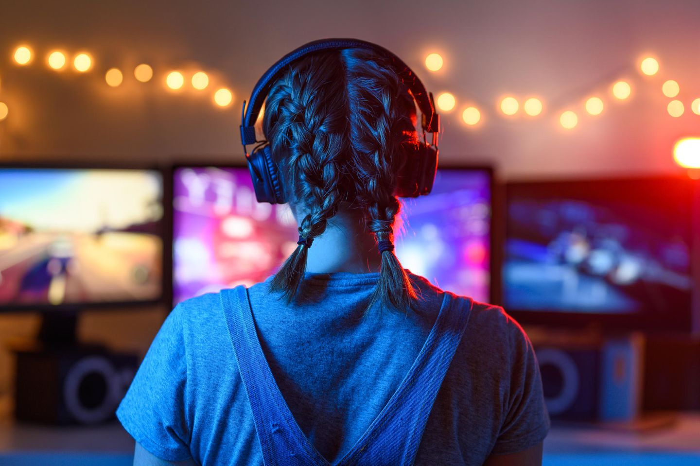 Experiment: eine Frau mit Kopfhörern sitzt vor Gaming Bildschirmen