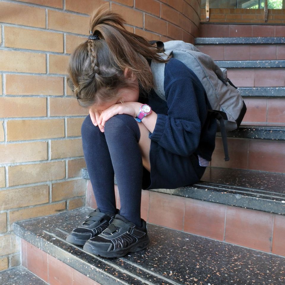 USA: Mädchen sitzt traurig auf Treppen der Schule