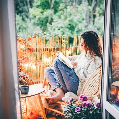 Frau liest auf dem Balkon: 4 lustige Liebesromane, die dich viel tiefer berühren werden als erwartet
