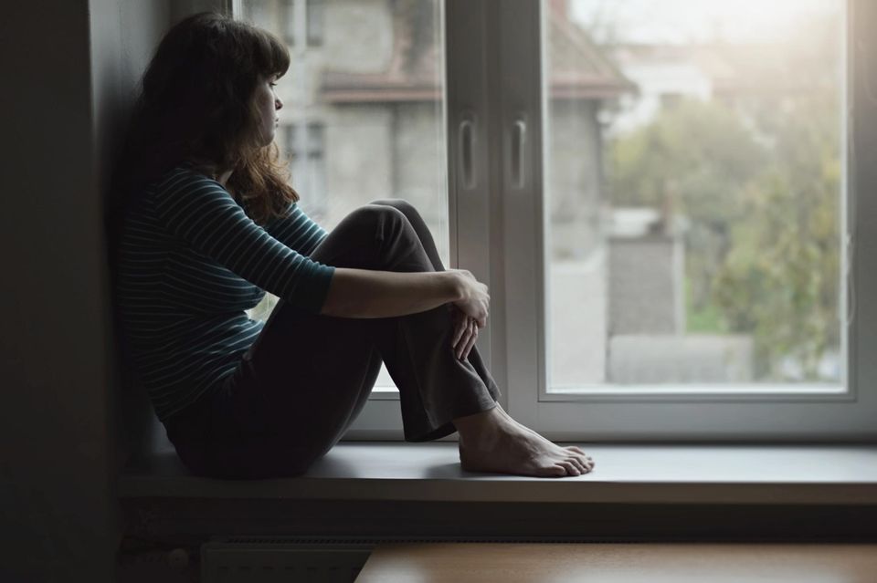 Single Kolumne: Nachdenkliche Frau sitzt am Fenster