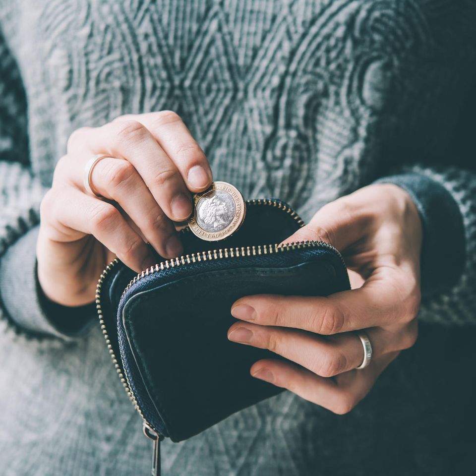 Eine Frau holt einen Euro aus ihrem Portemonnaie