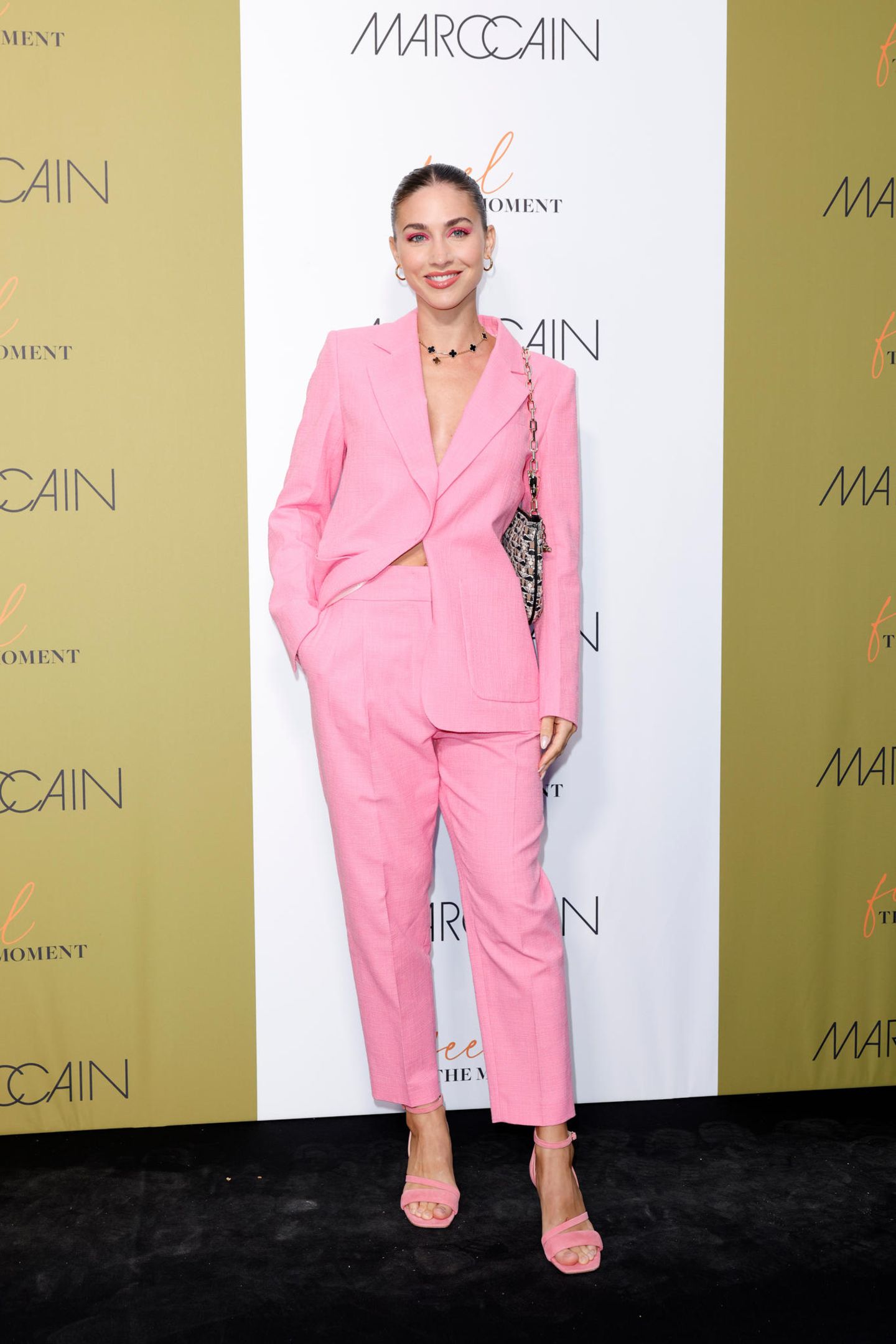 Ann-Kathrin Götze will sich die Fashion Show von Marc Cain nicht entgehen lassen und bezaubert dort im rosafarbenen Anzug-Look.