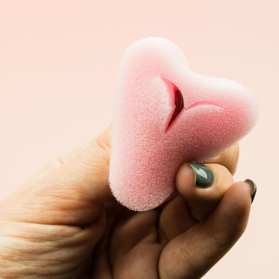Hand mit grünen Fingernägeln hält Soft-Tampon