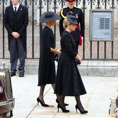 Herzogin Meghan und Gräfin Sophie kommen gemeinsam bei Westminster Abbey an. Beide tragen schwarze Trauerkleidung und Kopfbedeckungen. Besonders Meghans Look ist auffällig. Es scheint fast so, als hätte sie sich wieder einmal für ein Cape-Kleid von Stella McCartney entschieden. Das gleiche Modell, allerdings in Blau, trug sie das letzte Mal beim Geburtstagskonzert der Queen im Jahr 2018. 