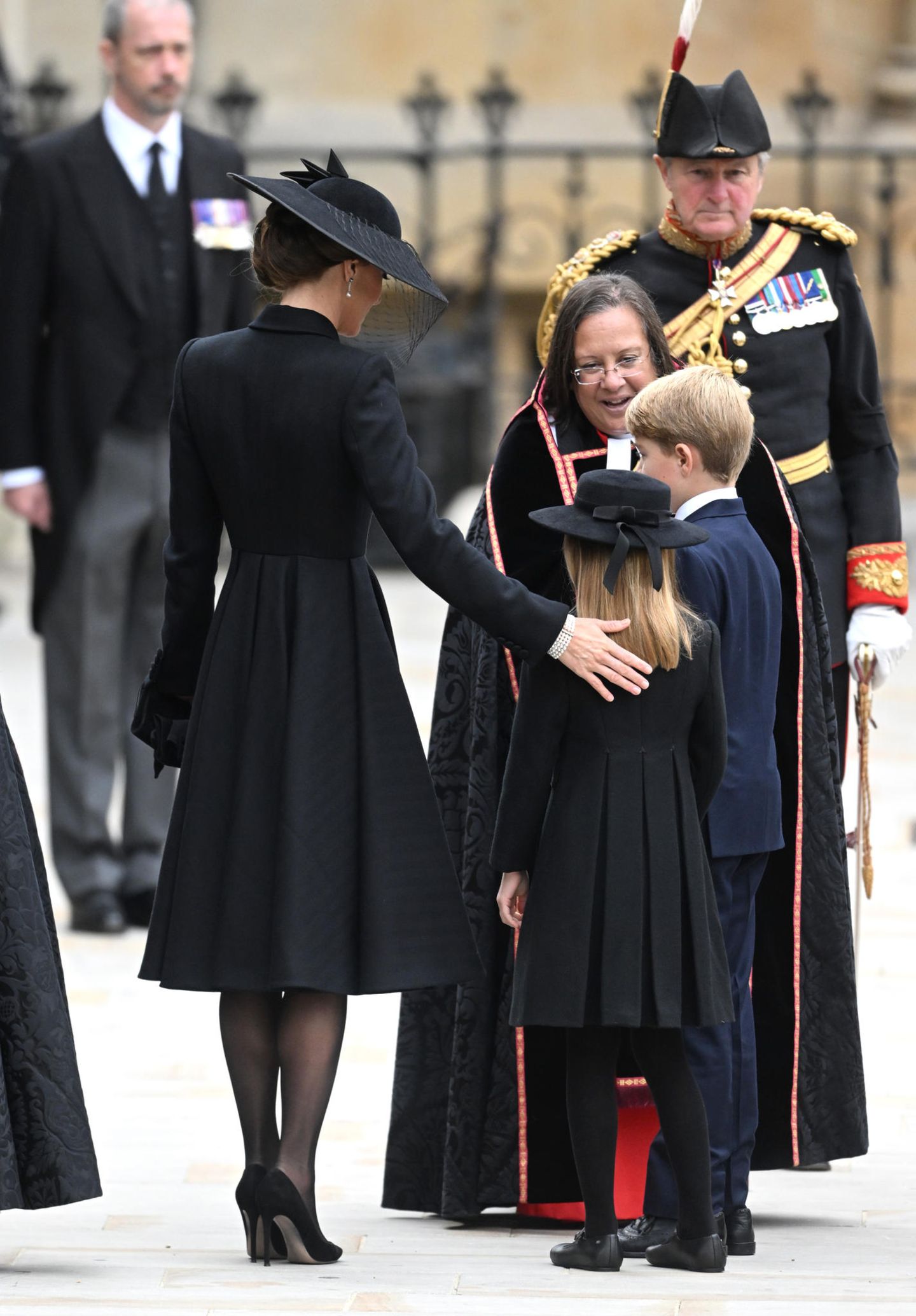 Der Apfel fällt nicht weit vom Stamm! Herzogin Catherine und Prinzessin Charlotte tragen beide einen schwarzen Mantel mit betonter Taille und Faltenlegung im Rock. Wie es das Protokoll vorschreibt, tragen sie dunkle Strumpfhosen und Schmuckstücke mit Bedeutung. 