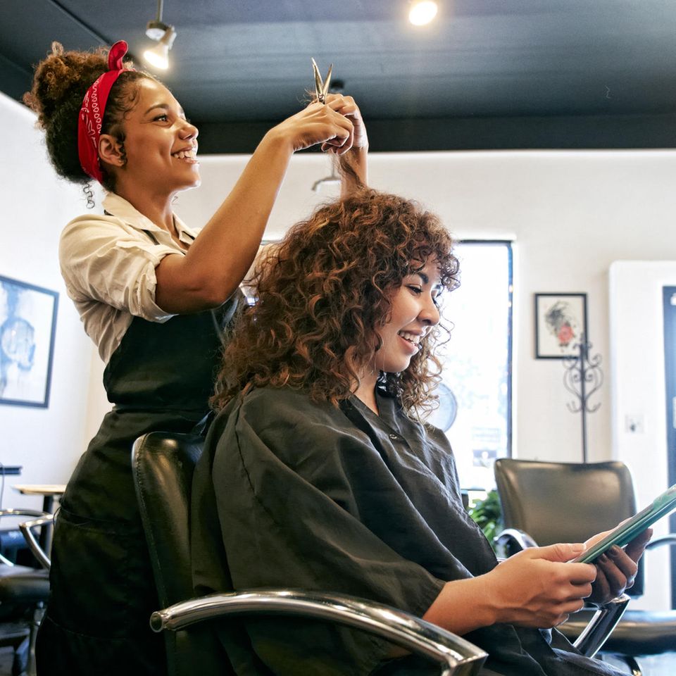 Eine Friseurin schneidet einer Frau die Haare.