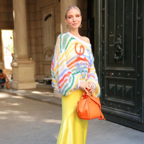 Farbenfroh mit gelbem Satin-Rock und buntem Strick-Pullover posiert Leonie Hanne kurz vor der Loewe Fashion Show für die Presse. 