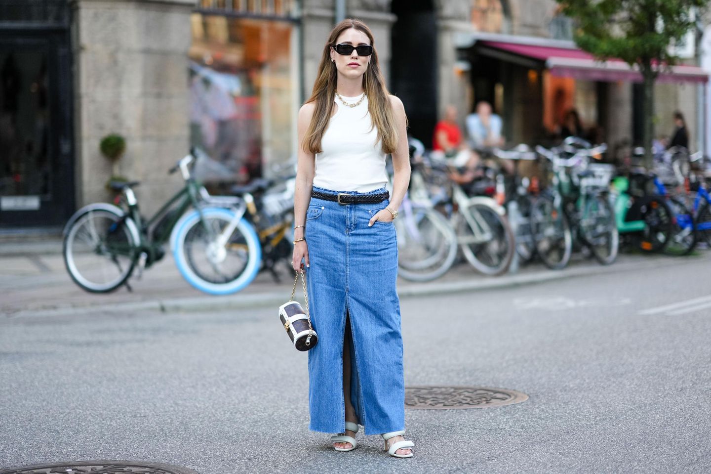 Annabel Rosendahl trägt einen langen Jeansrock mit weißem Top und Louis Vuitton Tasche.
