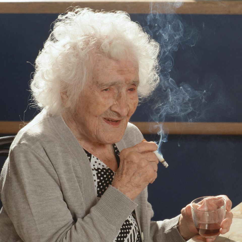 Jeanne Calment genießt an ihrem 117. Geburtstag ihre tägliche Zigaerette und ihr Glas Portwein 