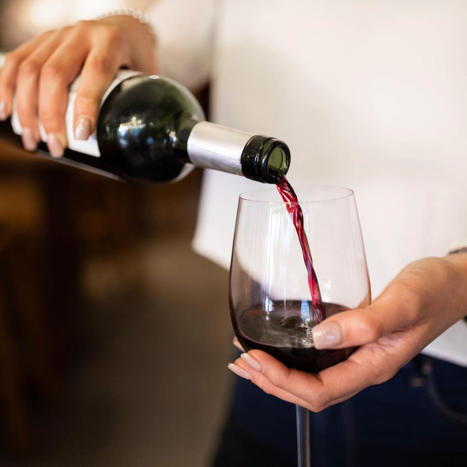 Eine Fru schüttet sich eine Flasche Rotwein ein.