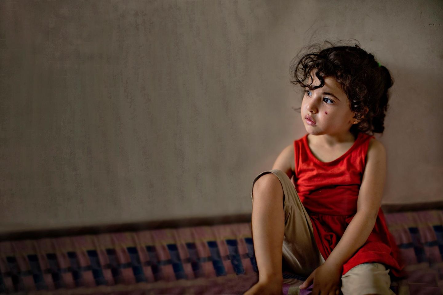 Ein Schal fürs Leben 2022: ein kleines Mädchen mit dunklen Haaren sitzt auf dem Boden