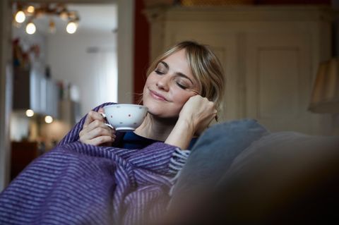 Gemütlichkeit: Frau mit Tee auf dem Sofa