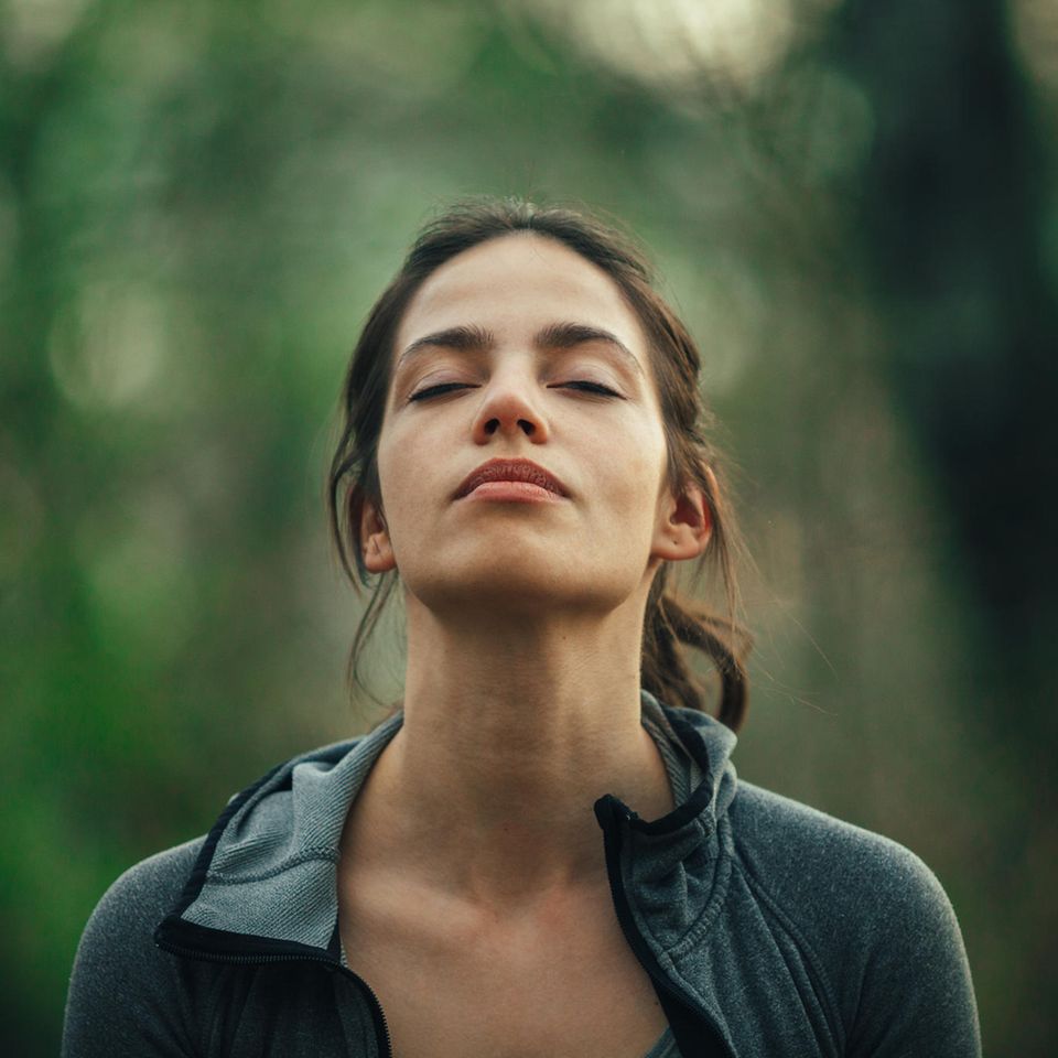 Frau mit geschlossenen Augen in der Natur: Diese Angewohnheit schadet deinem Gehirn mehr, als du denkst