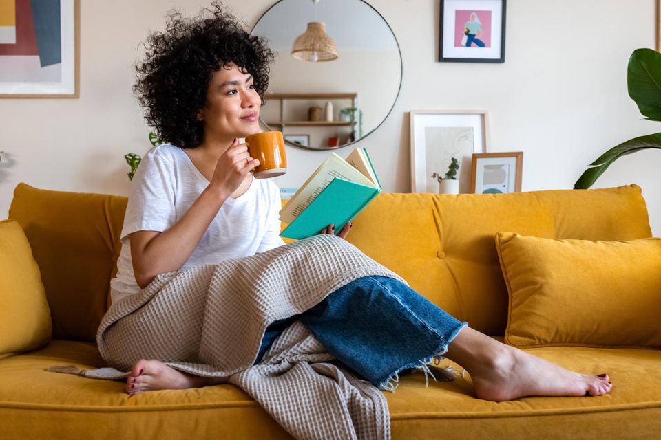 Good Vibes Wohntrend: Eine Frau trinkt einen Tee auf dem Sofa