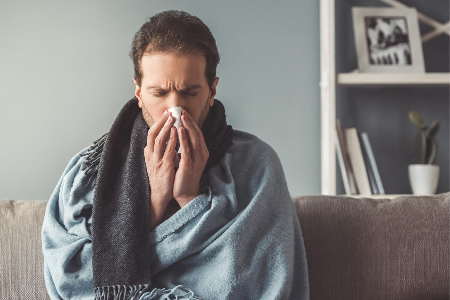 Grippe oder Erkältung: Kranker Mann putzt sich die Nase