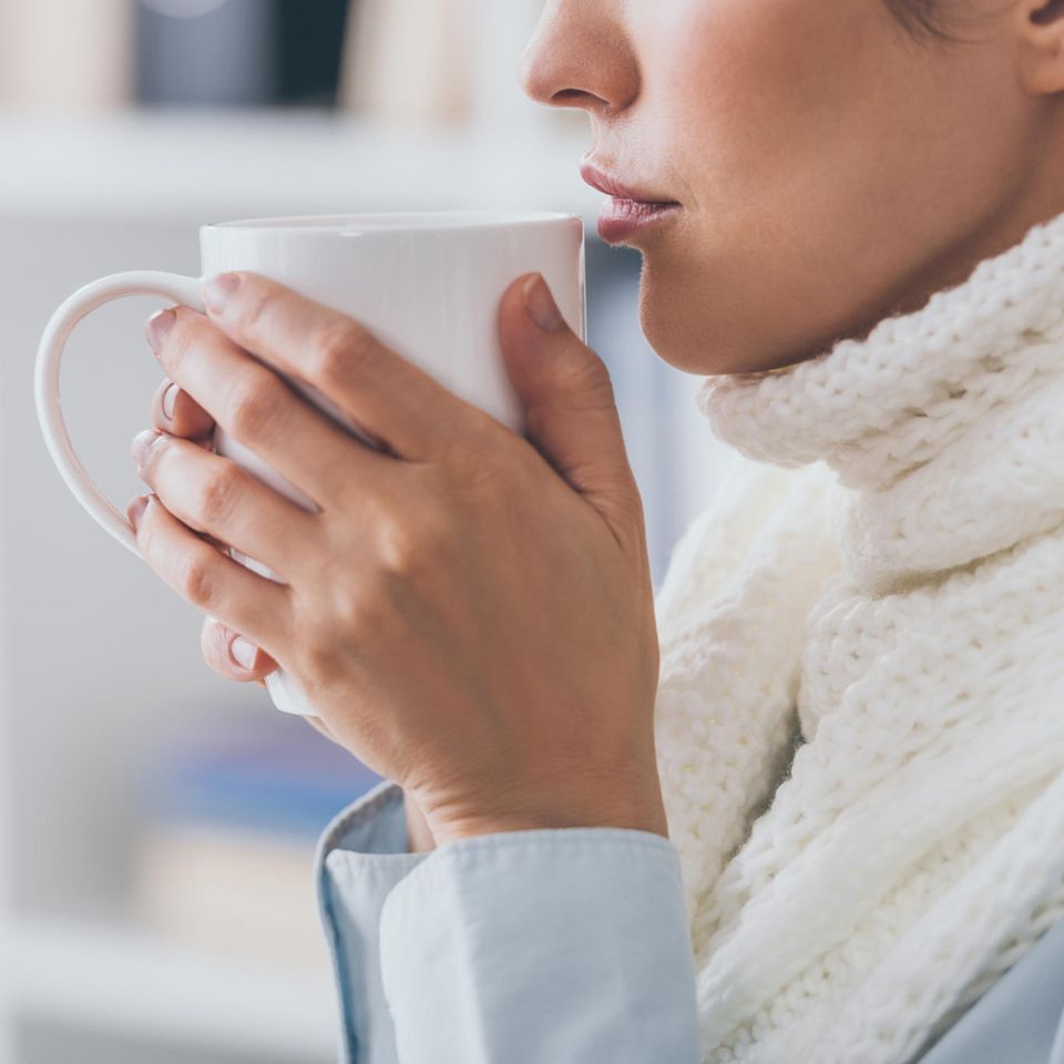 Schluckbeschwerden: Frau mit Halsschmerzen trinkt Tee