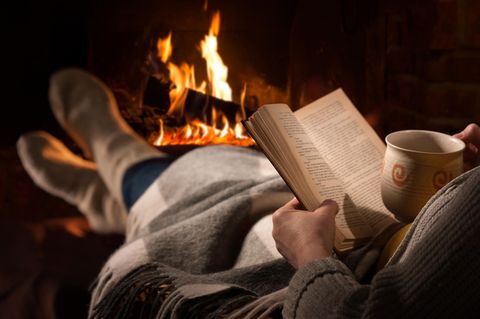Buchtrends Herbst 2022: Person sitzt lesend am Feuer