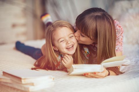 Buchtrends Herbst 2022: Frau küsst Tochter beim Vorlesen