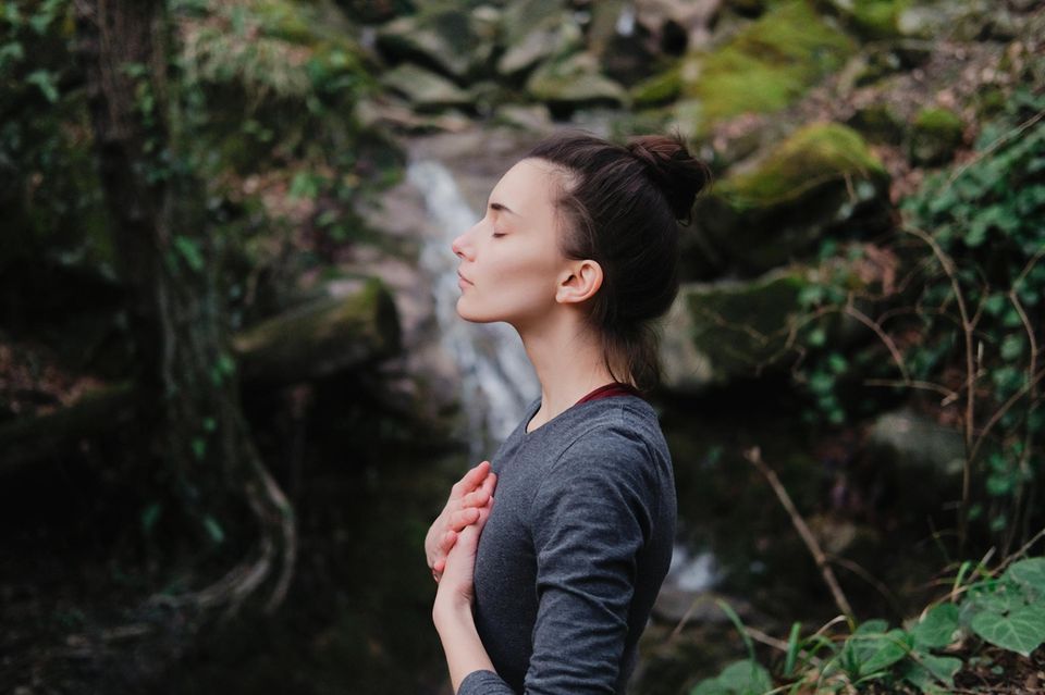 Frau in der Natur hört auf ihr Herz: 3 Anzeichen, dass du eine gute Intuition hast