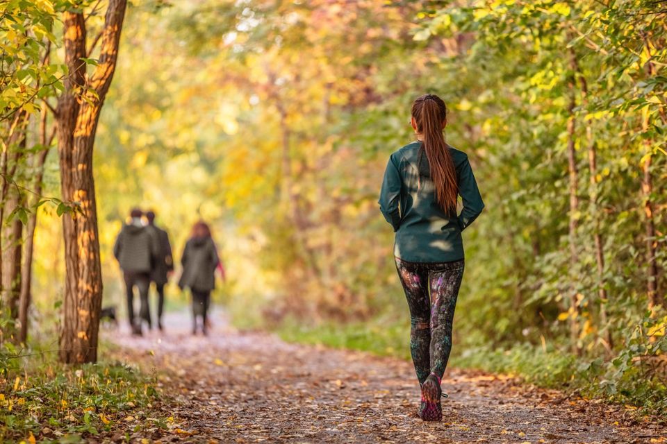 Frau geht im Park spazieren: 5 Gründe, warum du täglich spazieren gehen solltest