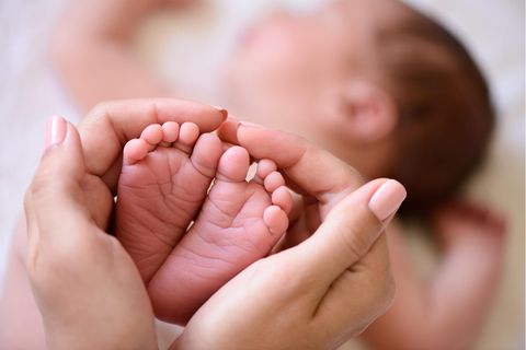 Neues Gesetz: Frauenhände halten Babyfüße