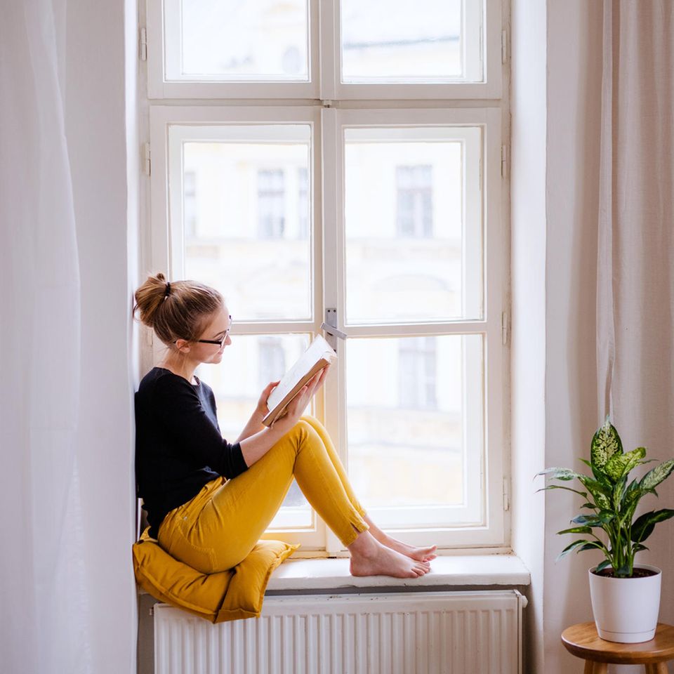 Frau liest ein Buch vor dem Fenster: Diese 5 Erfolgs-Serien beruhen auf richtig guten Büchern