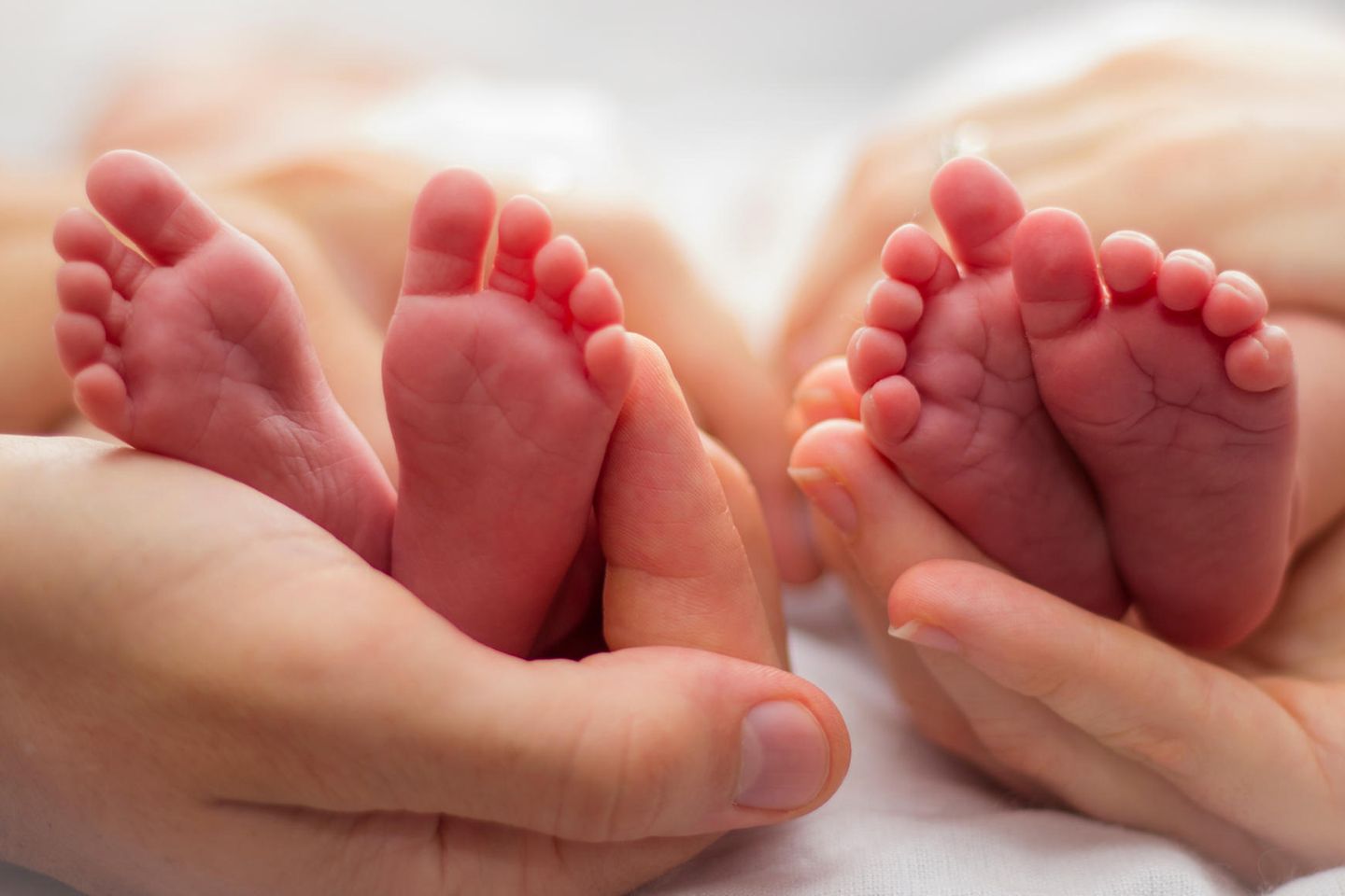 Paar bekommt Zwillinge – Hände halten die Füße von Zwillingen
