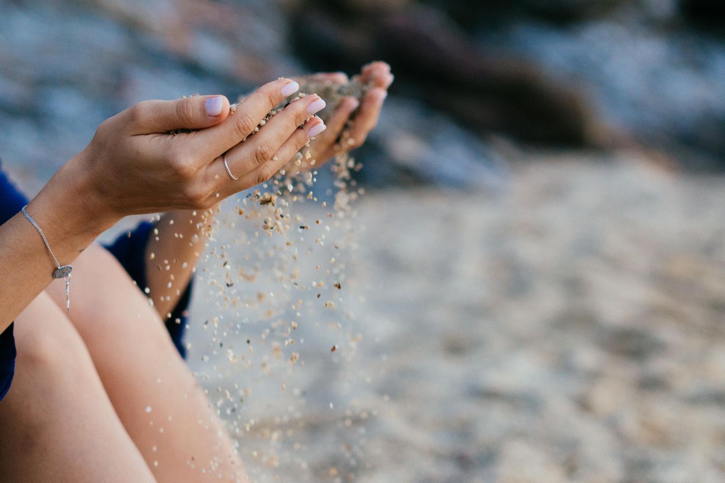 Abnehmen mit Sand: Frau lässt Sand durch die Finger rieseln
