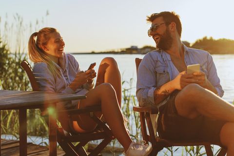 Oskar Holzbergs Liebeskolumne: Mann und Frau sitzen lachend am See