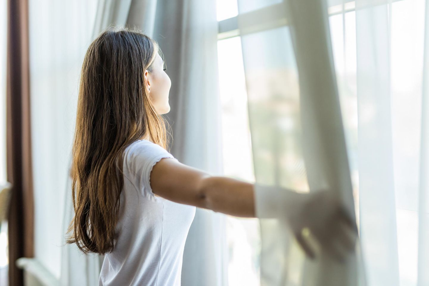 junge Frau schaut aus einem Fenster